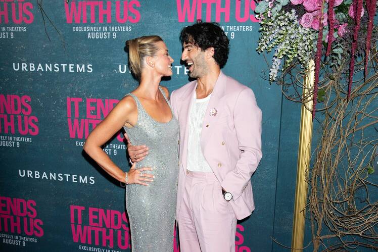 Justin Baldoni and his wife Emily Baldoni share a laugh while posing together on the red carpet at the It Ends With Us premiere.